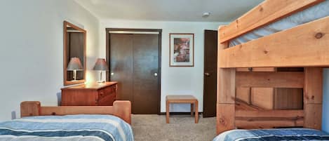 A bedroom with two beds, a dresser, a mirror, a door, and a small table.