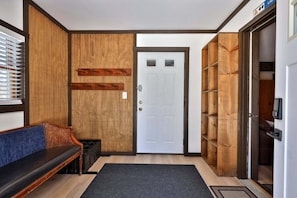 A hallway with a wooden door, a bench, and a shoe rack. - Liquid Lodge Lower: 2BR Duplex near Killington with 4 PM Checkout (Killington)