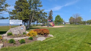 A park with a playground, a sign reading 'Patterson Park,' and a body of water in the background. - 3 Bdrm | BBQ | Fire Pit - Steps to Waterfront Park (Port McNicoll)