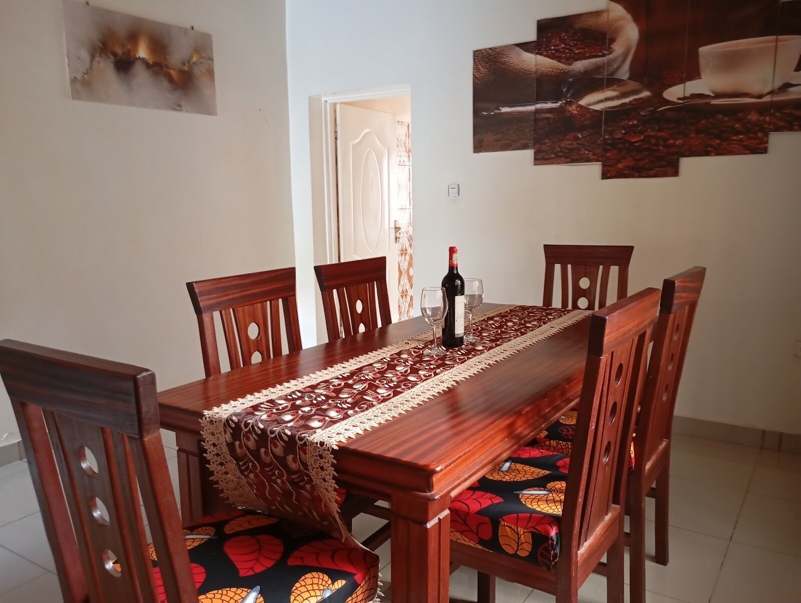 Un coin repas avec une table en bois, des chaises et un chemin de table en dentelle.