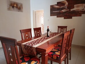 A dining area with a wooden table, chairs, and a lace table runner.