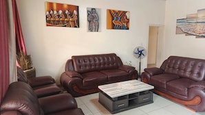 A living room with two brown leather sofas, a coffee table, and wall art. - Sunset Retreat Home (Kigali city)