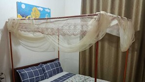 A single bed with a canopy, a wooden headboard, and a floral bedspread. - Sunset Retreat Home (Kigali city)