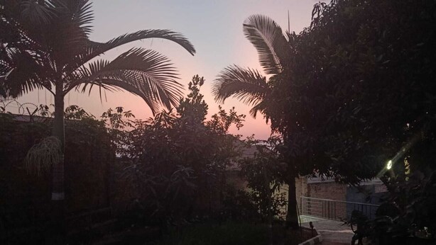 A pathway leading to a gated area with a brick wall and a motorcycle parked nearby. - Sunset Retreat Home (Kigali city)
