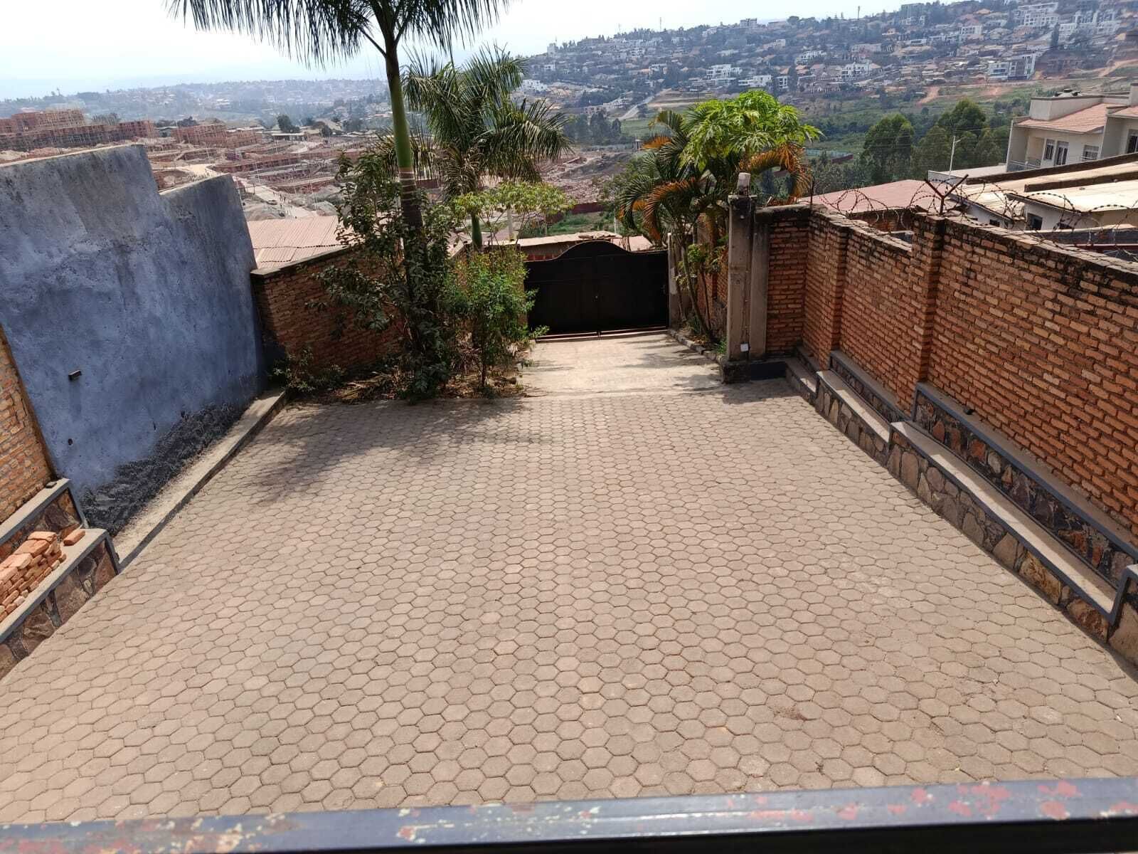 A rooftop terrace with a hexagonal tile floor, brick walls, and a view of a residential area in the background.
