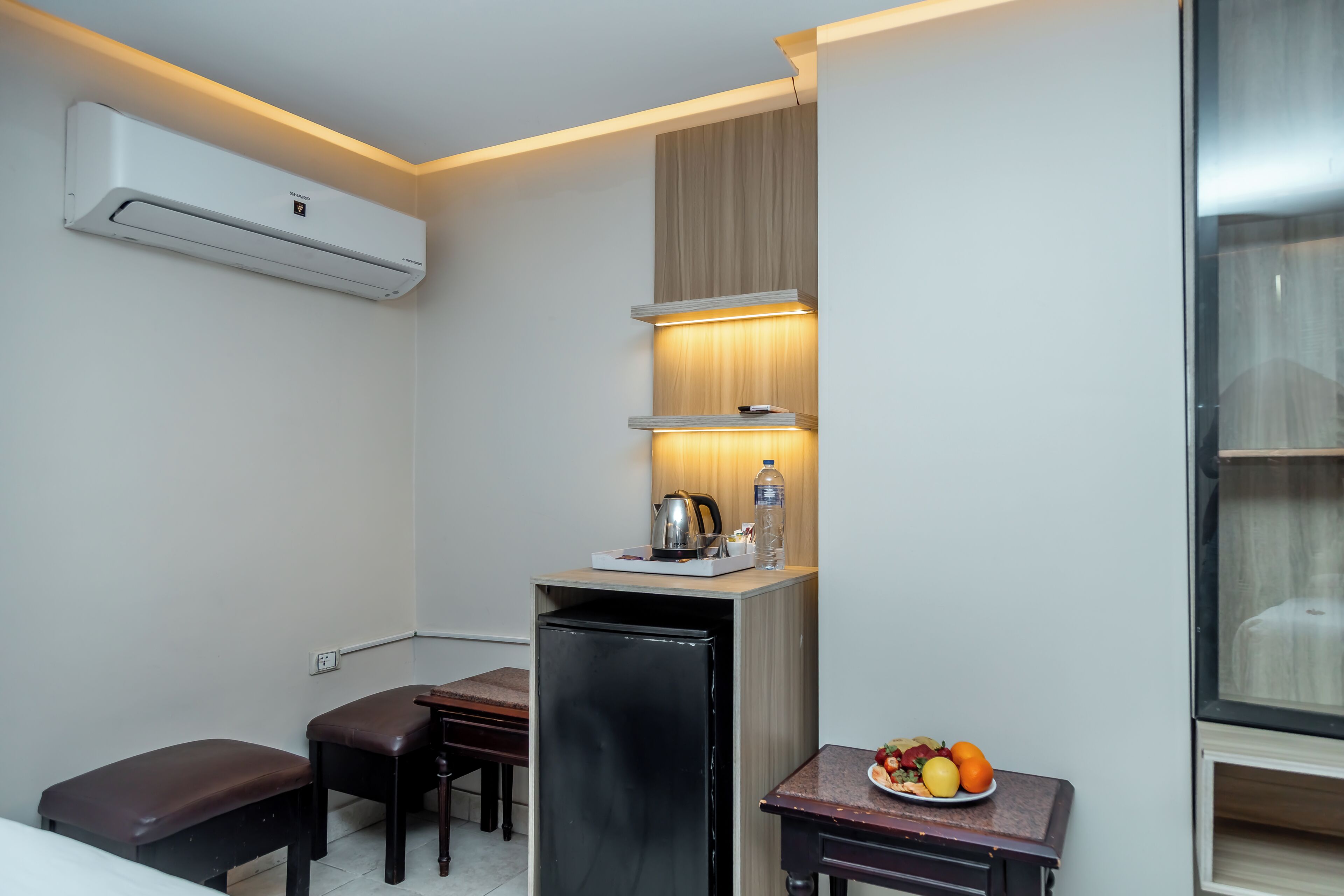 A compact kitchenette with a refrigerator, a small dining table, and a bench.