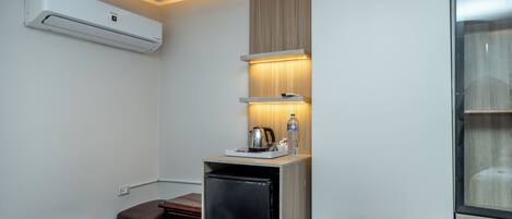 A compact kitchenette with a refrigerator, a small dining table, and a bench.