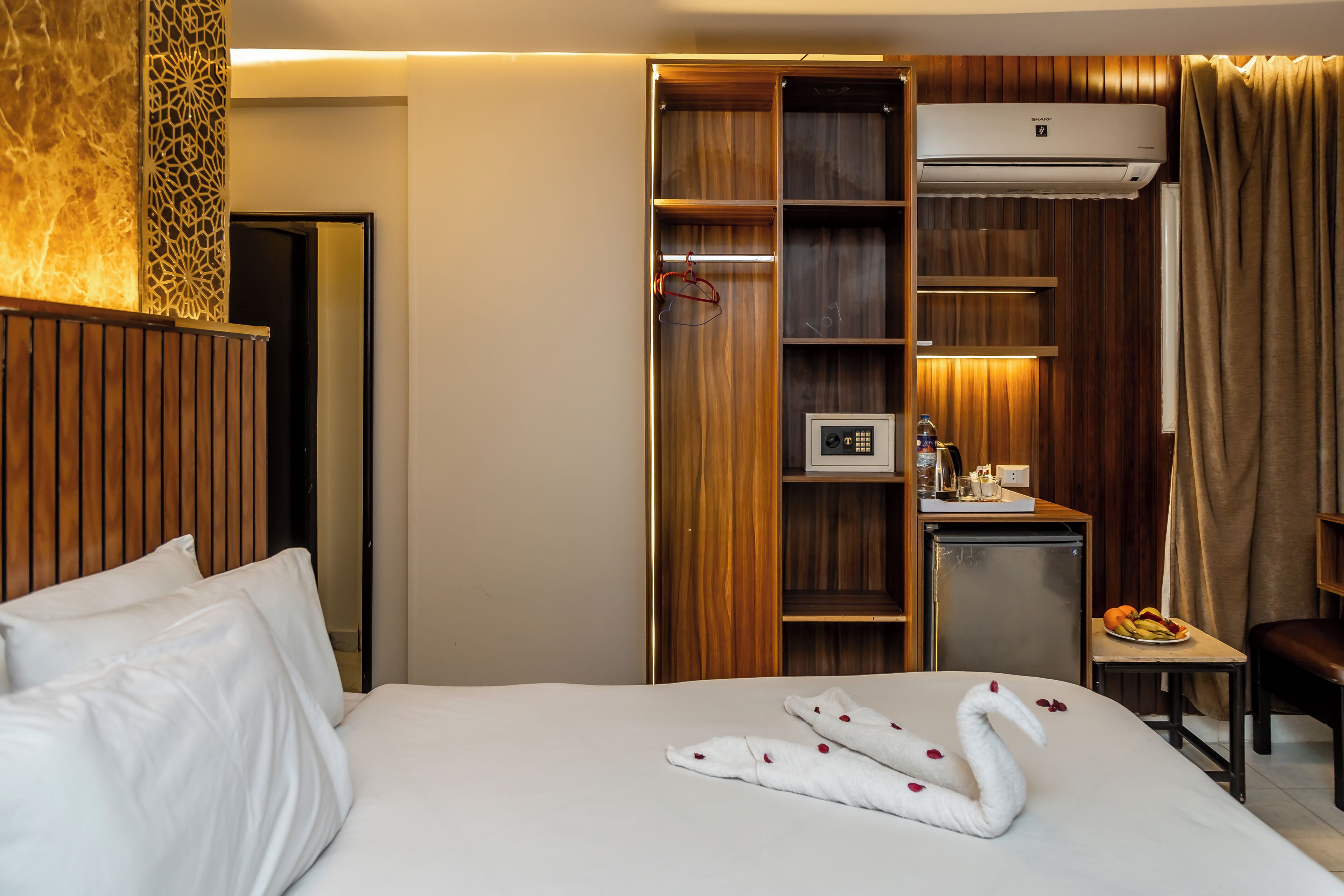 Une chambre d’hôtel équipée d’un lit, d’un bureau avec un ordinateur, d’un mini-bar et d’une armoire.
