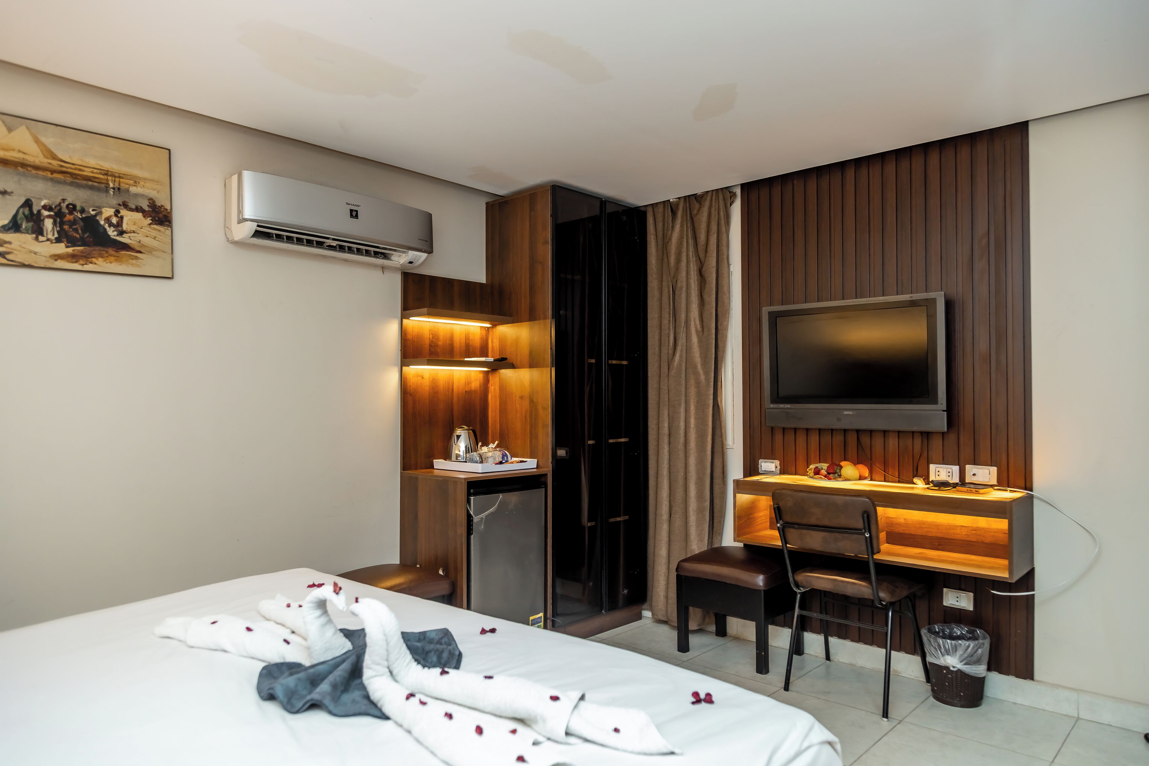 A hotel room with a bed, a desk, a television, and a minibar.