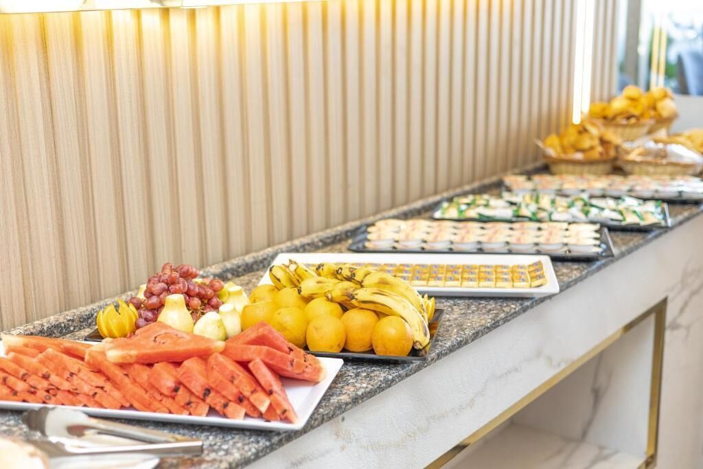 A buffet with various food items including fruits, vegetables, and pastries.