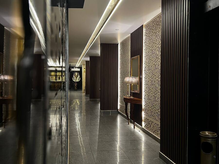 A modern hotel lobby with a reflective floor, a decorative wall panel, and a lamp.