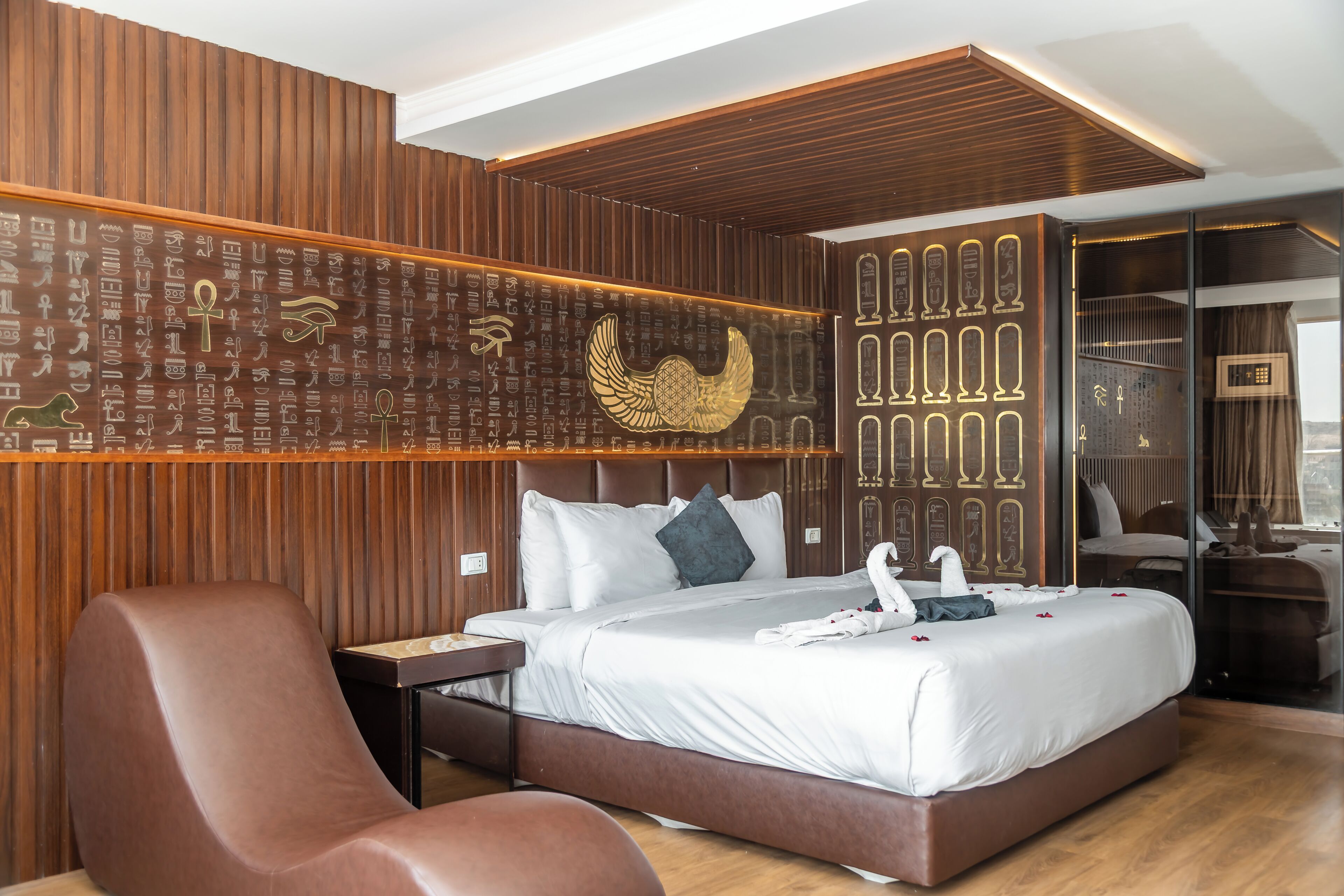 Et moderne hotelværelse med en seng, et siddeområde og en væg udsmykket med hieroglyffer.