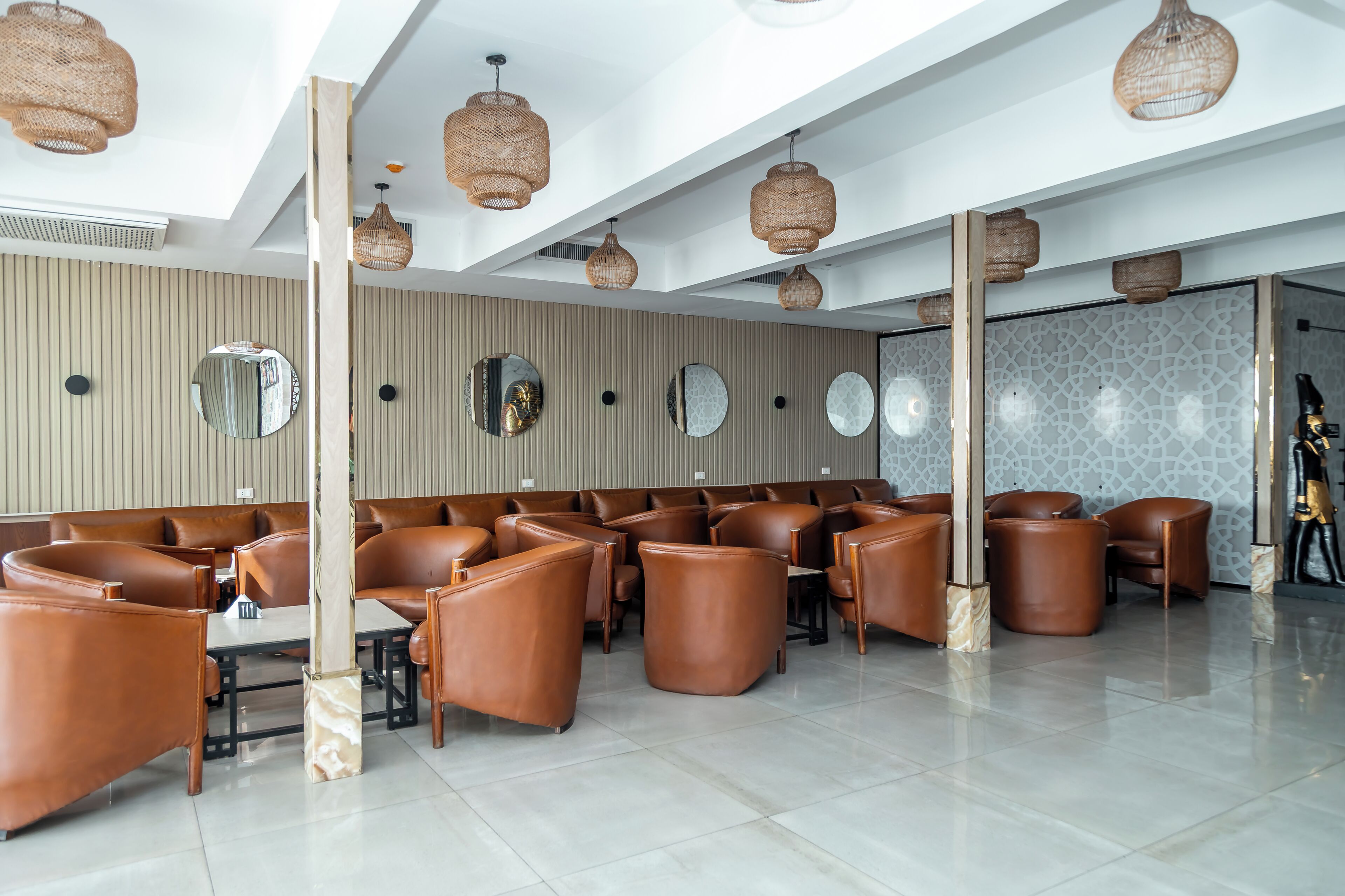 A modern interior with leather seating, woven light fixtures, and decorative mirrors.