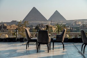 A terrace with two chairs facing a view of two pyramids.