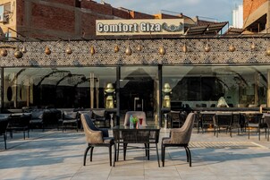 A cafe named Comfort Giza with outdoor seating and a patterned facade.