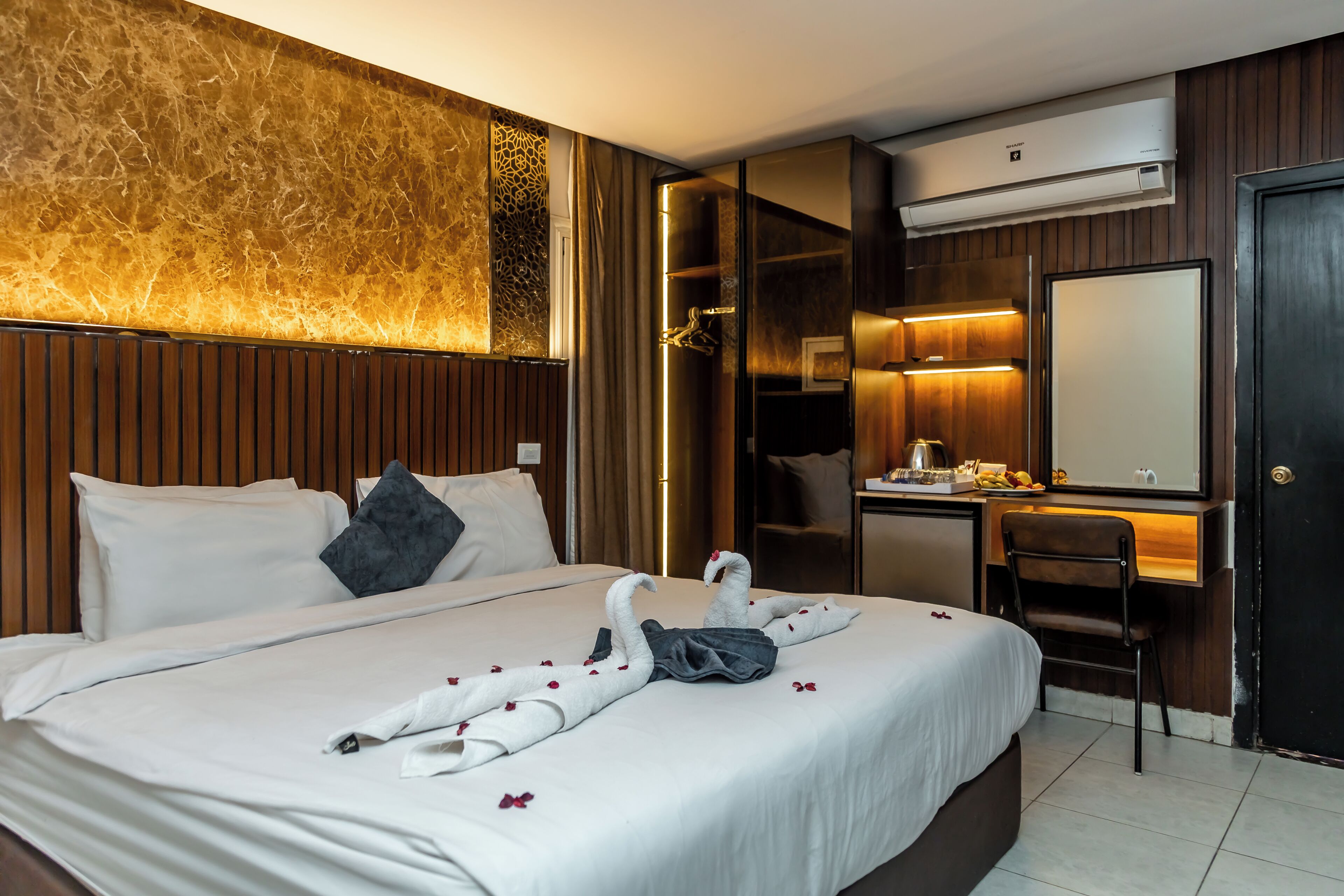 A hotel room with a bed, a desk, a chair, and a wardrobe.