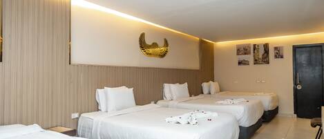 Habitació d'hotel amb tres llits, un objecte decoratiu penjat a la paret i una porta.