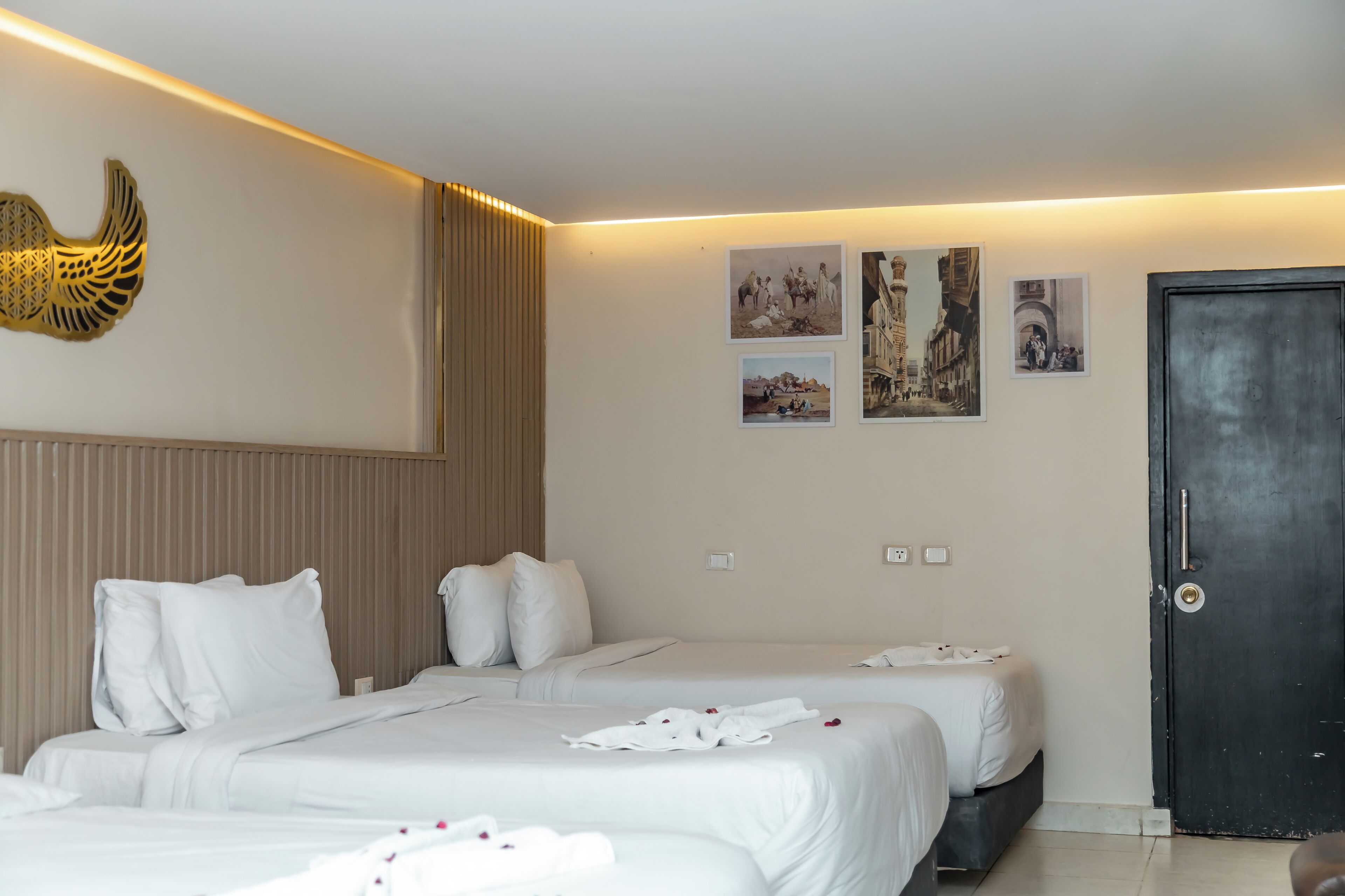 Habitación de hotel con dos camas, una puerta oscura y decoración en la pared.