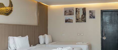 Habitación de hotel con dos camas, una puerta oscura y decoración en la pared.