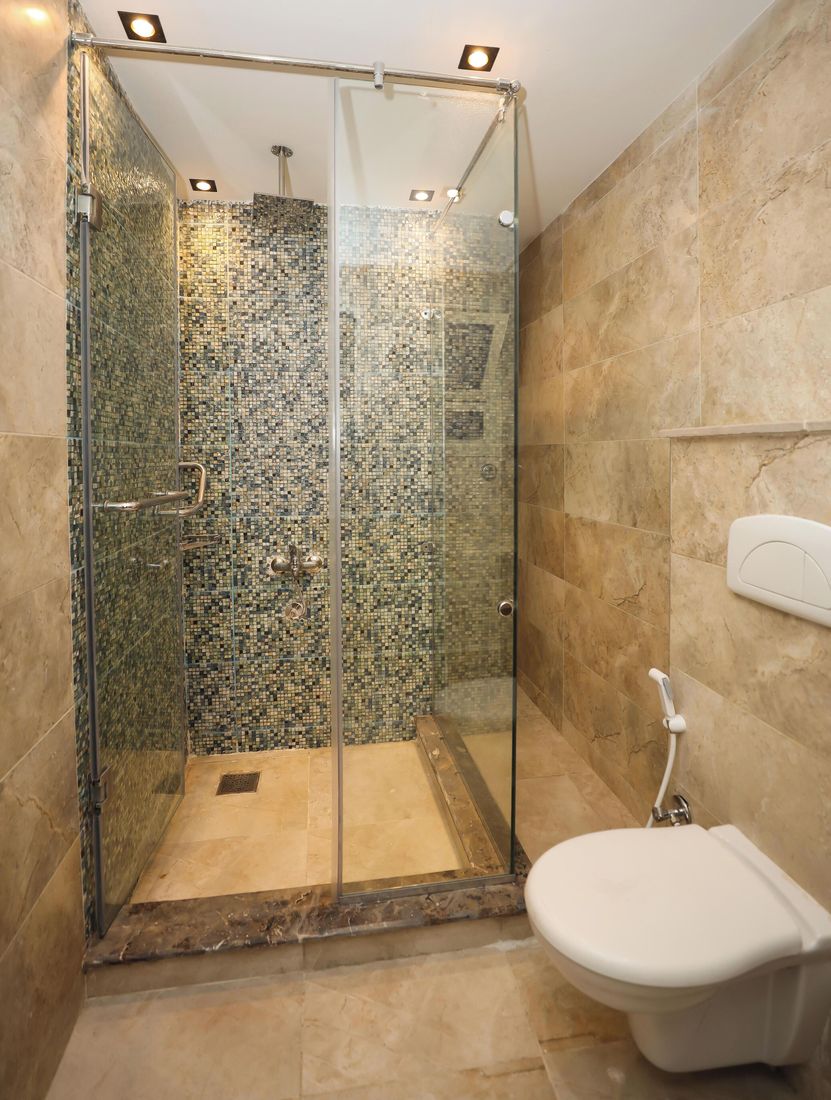 A shower with a glass door, a tiled wall, and a toilet.