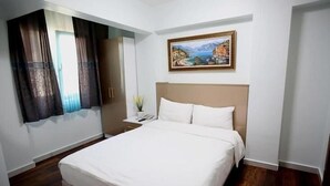 A hotel room with a bed, a nightstand, a mirror, and a painting on the wall.