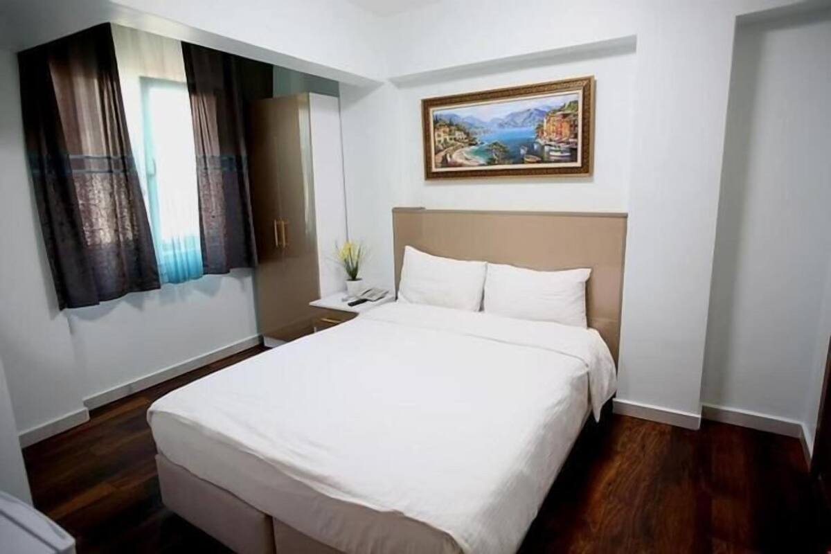 A hotel room with a bed, a nightstand, a mirror, and a painting on the wall.