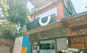 Un hotel boutique con un letrero llamativo, un acceso con portones y un balcón visible.