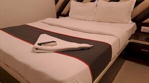 A hotel room with a bed, pillows, a remote control, and a nightstand. - Classic Collection O Kurla BKC Mumbai (Mumbai)