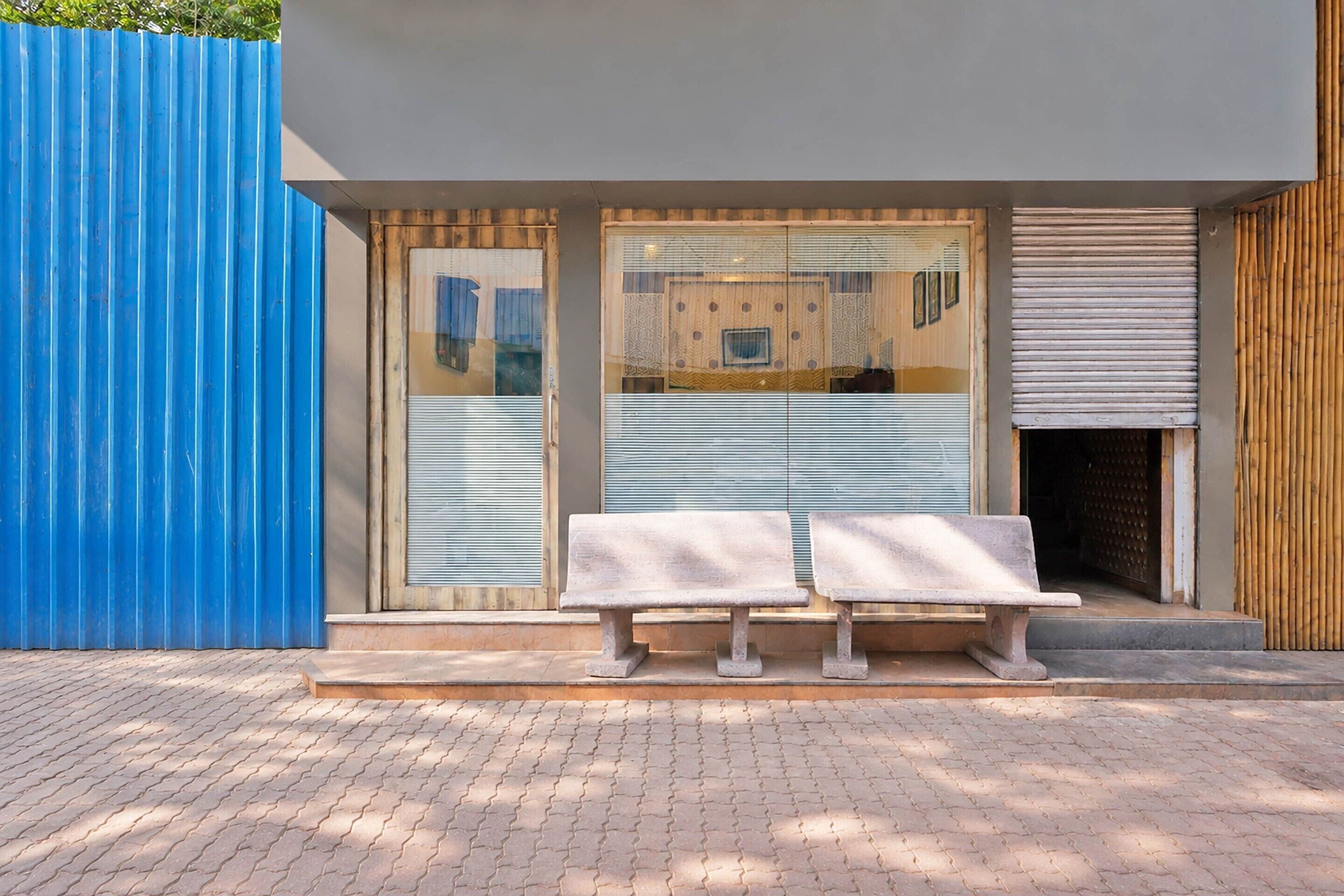 Un edificio moderno con un muro exterior azul, una puerta de madera y un par de bancos de piedra en la fachada.