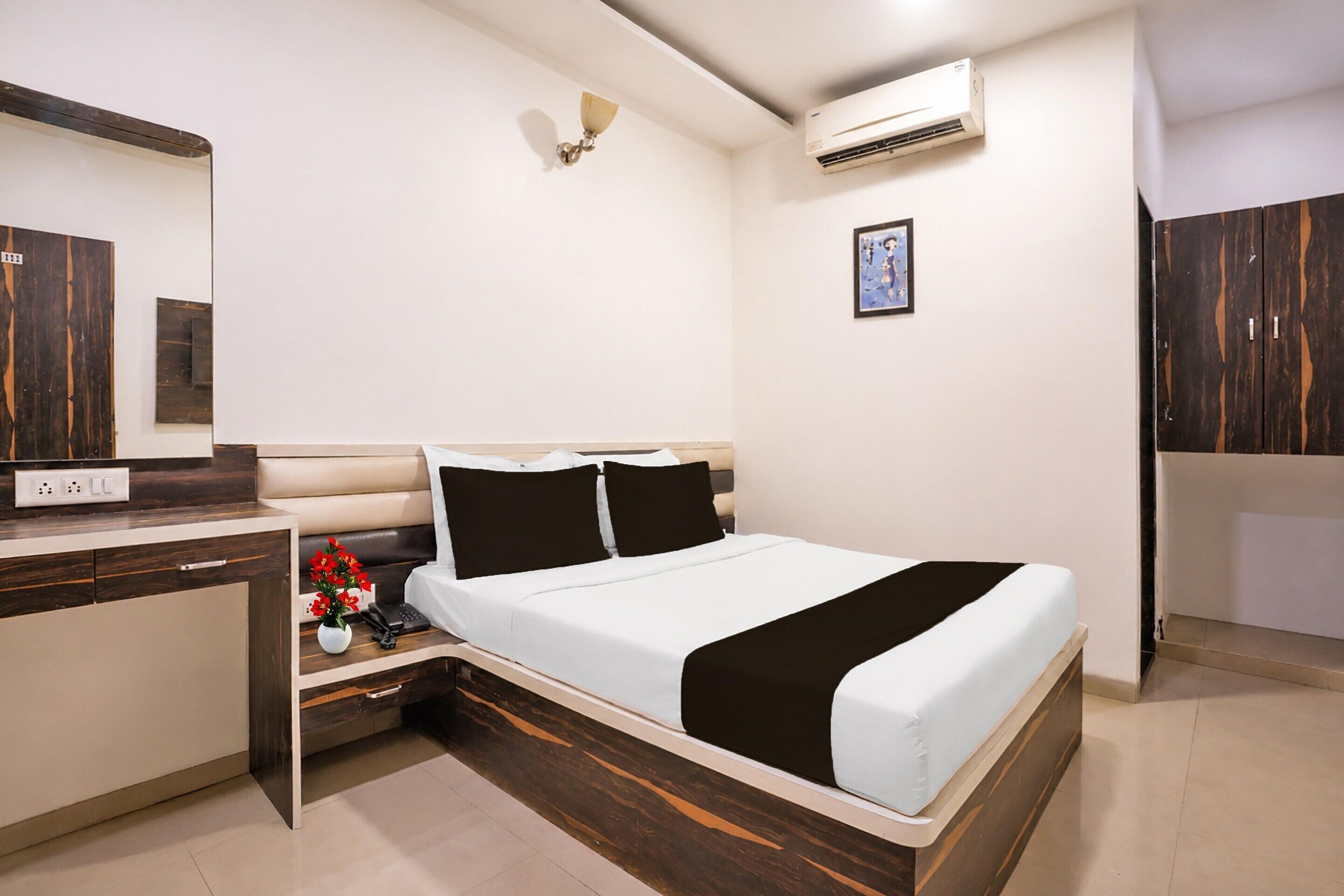 A bedroom with a bed, bedside table, and a mirror.