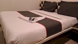 A neatly made bed with a white and gray bedspread, a remote control, and a small box on the bed. - Classic Collection O Kurla BKC Mumbai (Mumbai)