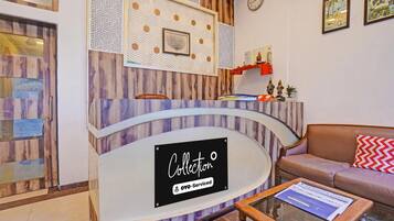 A reception desk with a sign reading 'Collection OYO-Serviced' and a clock on the wall.