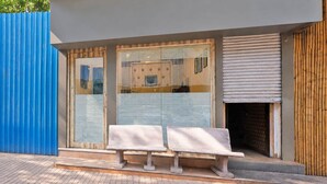 A building with two benches outside, a blue wall to the left, and a wooden door to the right. - Classic Collection O Kurla BKC Mumbai (Mumbai)