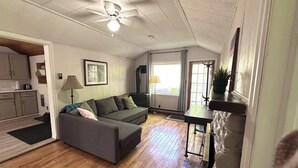 A living room with a sofa, a lamp, a fireplace, and a kitchen area.