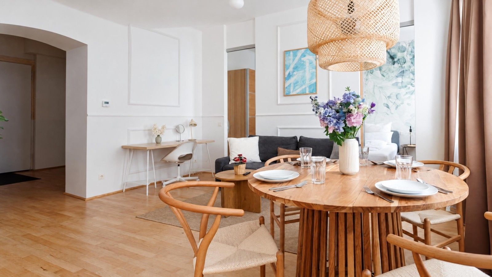 A dining area with a round wooden table set for four, surrounded by wooden chairs.