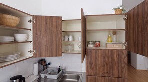 A kitchen with wooden cabinets, a sink, and a tea storage area. - Elegant 2-room studio apartment (Österreich)