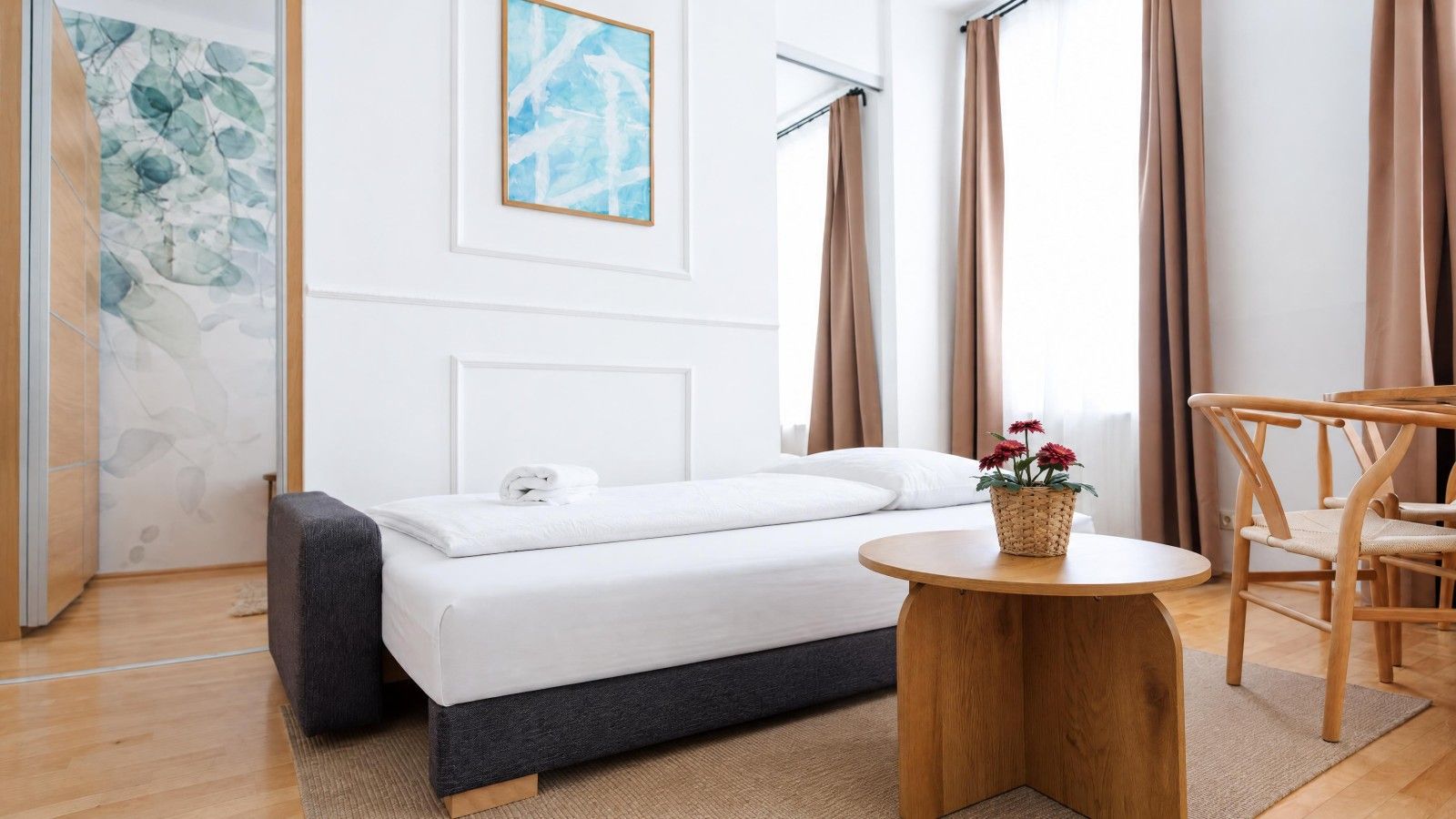 A modern bedroom with a bed, a round wooden table, and a chair.
