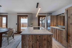 A modern kitchen with a central island, wooden paneling, and a view to the outside. - 100m from resort center, 1st floor, terrace, fireplace or stove, 150m², Champagny-en-Vanoise (Champagny-en-Vanoise)