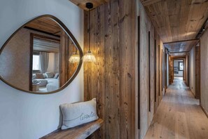 A hallway with wooden paneling, a round mirror, and a bench with a cushion. - 100m from resort center, 1st floor, terrace, fireplace or stove, 150m², Champagny-en-Vanoise (Champagny-en-Vanoise)