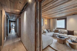 A modern interior with a wooden ceiling, a hallway leading to a living area with a sofa set and a fireplace. - 100m from resort center, 1st floor, terrace, fireplace or stove, 150m², Champagny-en-Vanoise (Champagny-en-Vanoise)
