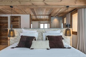 A bedroom with a wooden ceiling, a bed with white and brown pillows, and a mirror above the bed. - 100m from resort center, 1st floor, terrace, fireplace or stove, 150m², Champagny-en-Vanoise (Champagny-en-Vanoise)