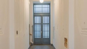 Um corredor com porta dupla, paredes brancas e ladrilhos de chão estampados.