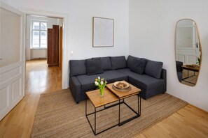 A modern living room with a grey sectional sofa, a wooden coffee table, and a mirror on the wall. - Oona Residence Vienna (Österreich)