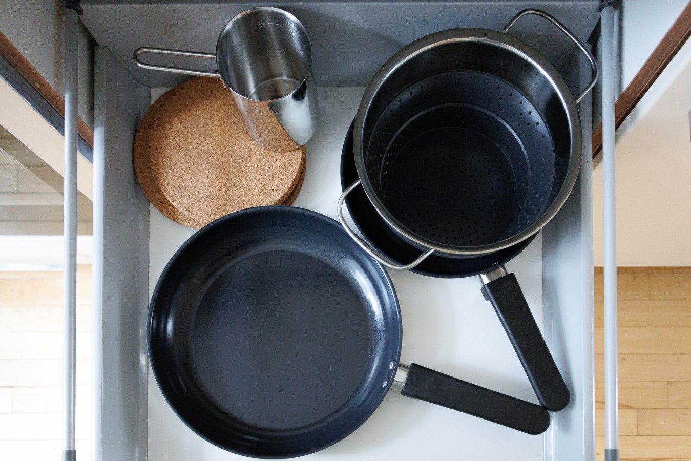 Een keuken met een fornuis, een koekenpan, een pan en een maatbeker.