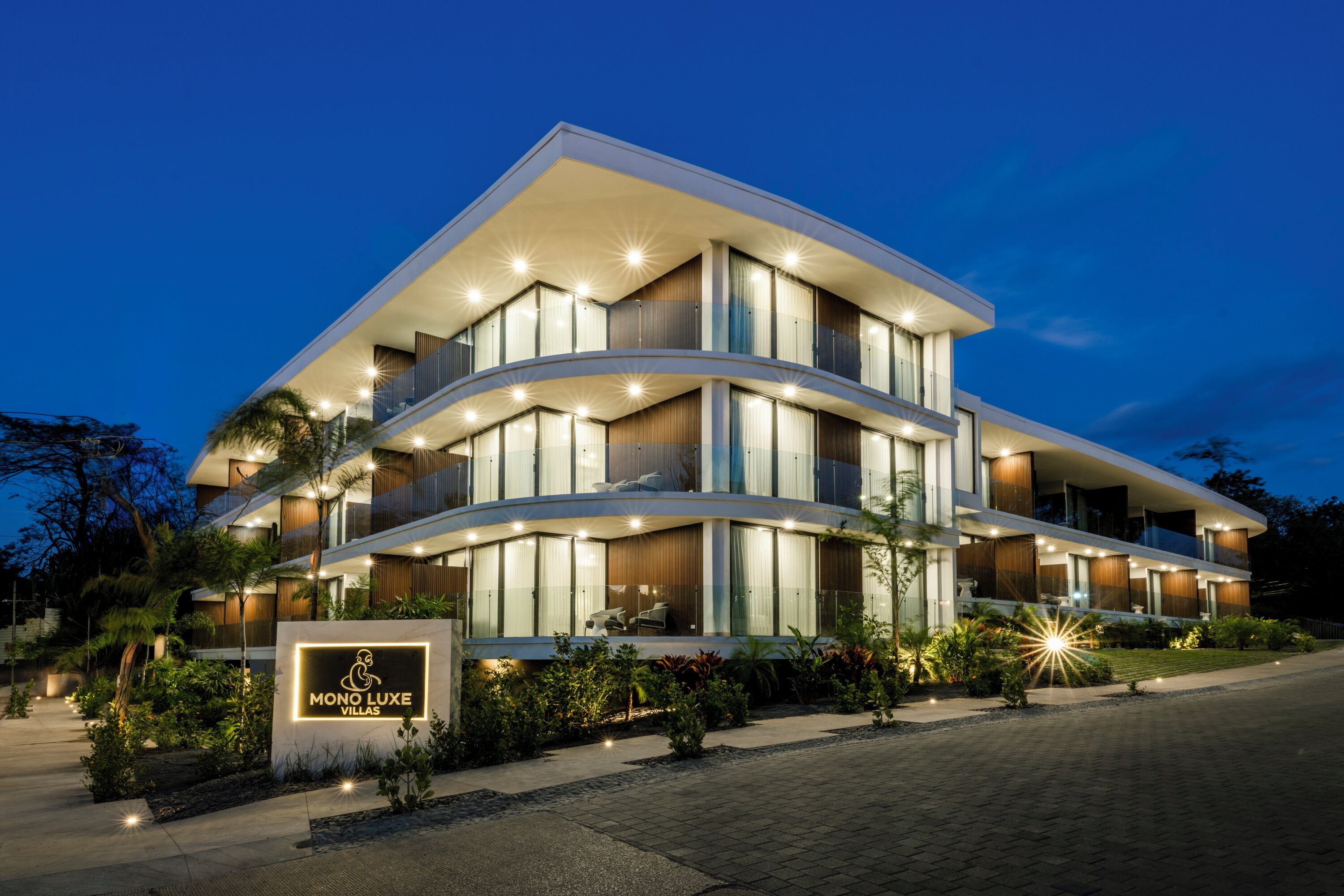 Una villa moderna con facciata curva, diversi balconi e un ingresso ben illuminato.