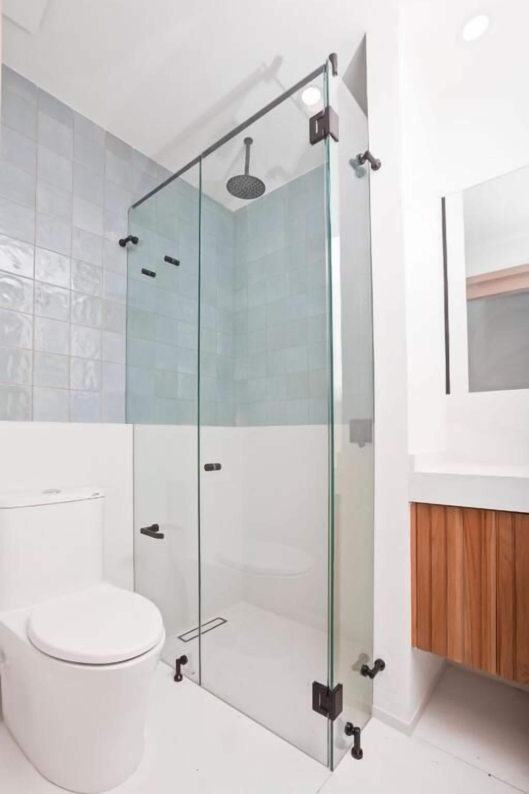 Une salle de bain moderne avec une douche à parois de verre, des toilettes blanches et un meuble-lavabo en bois.