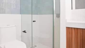 Une salle de bain moderne avec une douche à parois de verre, des toilettes blanches et un meuble-lavabo en bois.