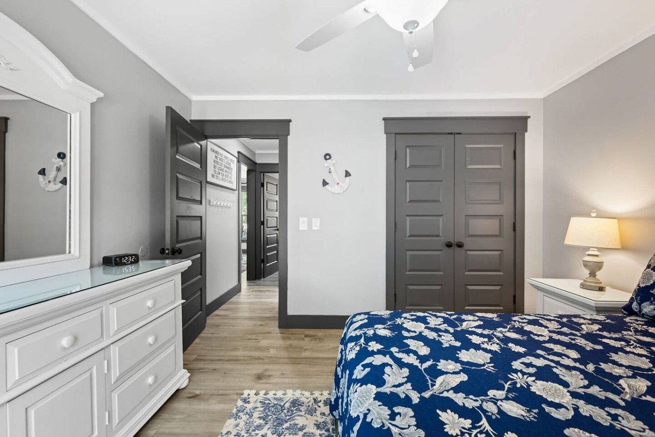 A bedroom with a bed, dresser, and a ceiling fan.