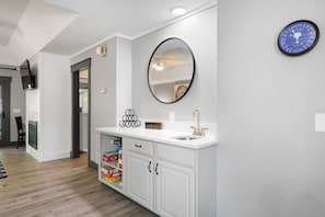 Une salle de bain moderne avec un meuble-lavabo blanc, un miroir rond et une horloge murale.