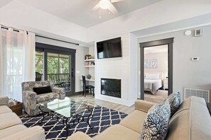 Ein modernes Wohnzimmer mit Kamin, Glastisch und Sofa.